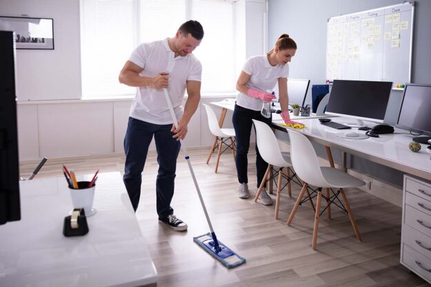Smiling Two Young Janitor Cleaning The Office Profesjonalne mopy i systemy do mycia podłóg